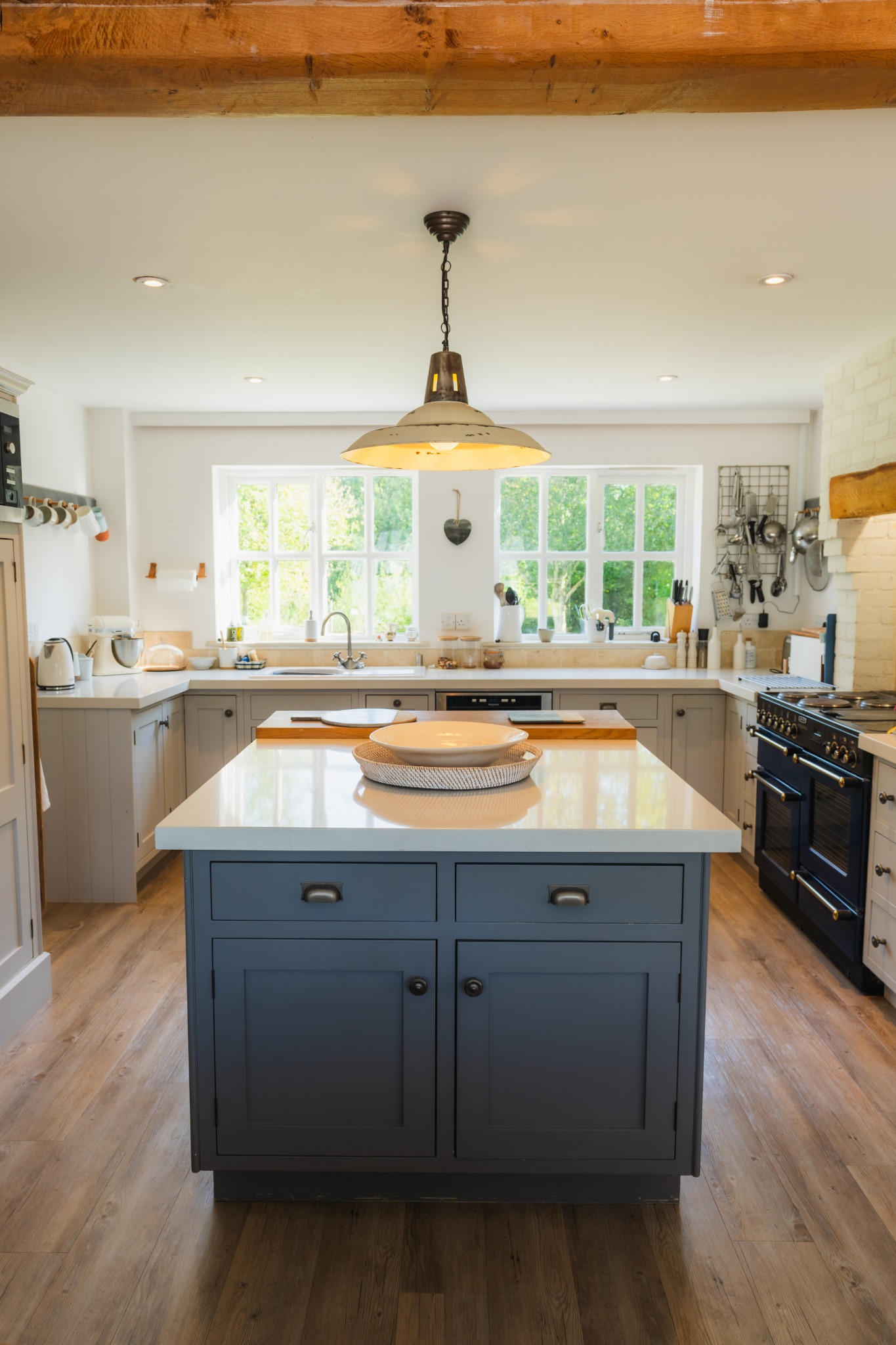 Paddock House’s farmhouse-style kitchen with a blue-grey island, pendant light and timber beams