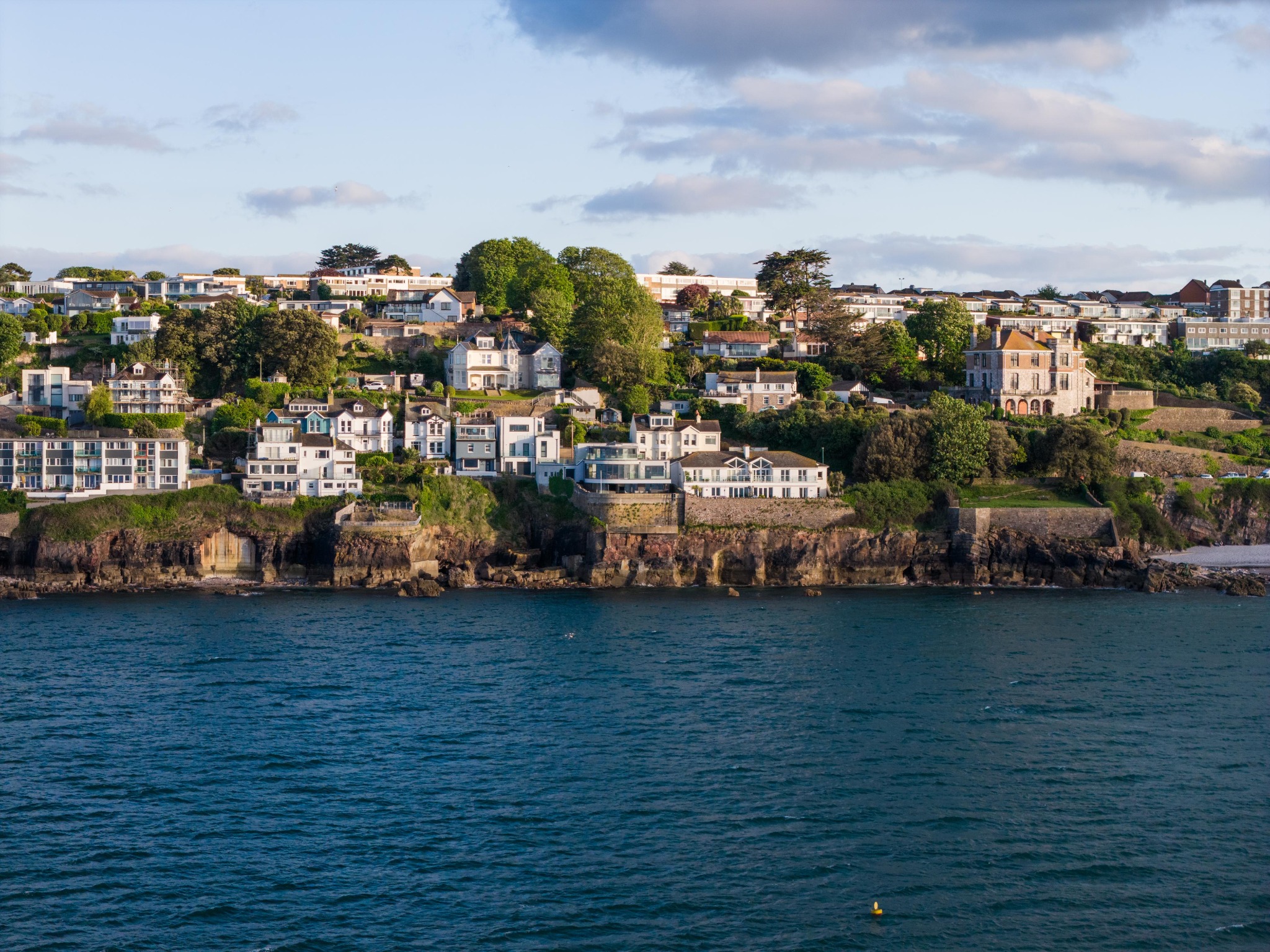 Coastal homes above the blue waters of Brixham, photographed from the sea